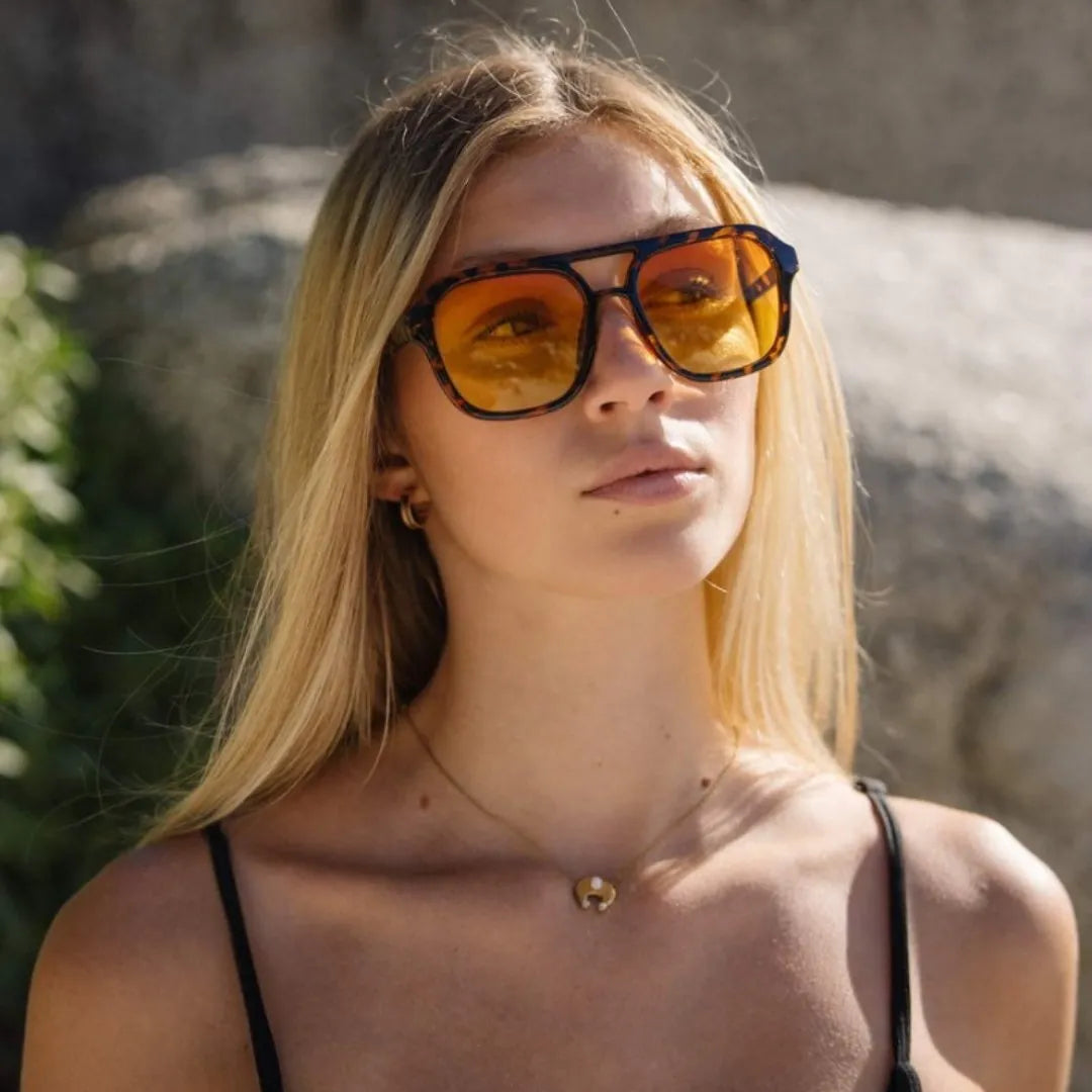 a woman wearing bold retro yellow tinted sunglasses with tortoiseshell frame