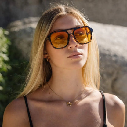 a woman wearing bold retro yellow tinted sunglasses with tortoiseshell frame