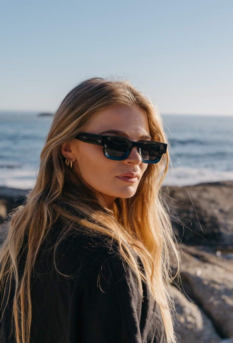 Woman wearing black rectangle new wave sunglasses with black frame and smoke grey UV protection lens – bold retro chunky rectangle shades styled for holidays and summer city wear, Sunglass Station free UK and Europe shipping