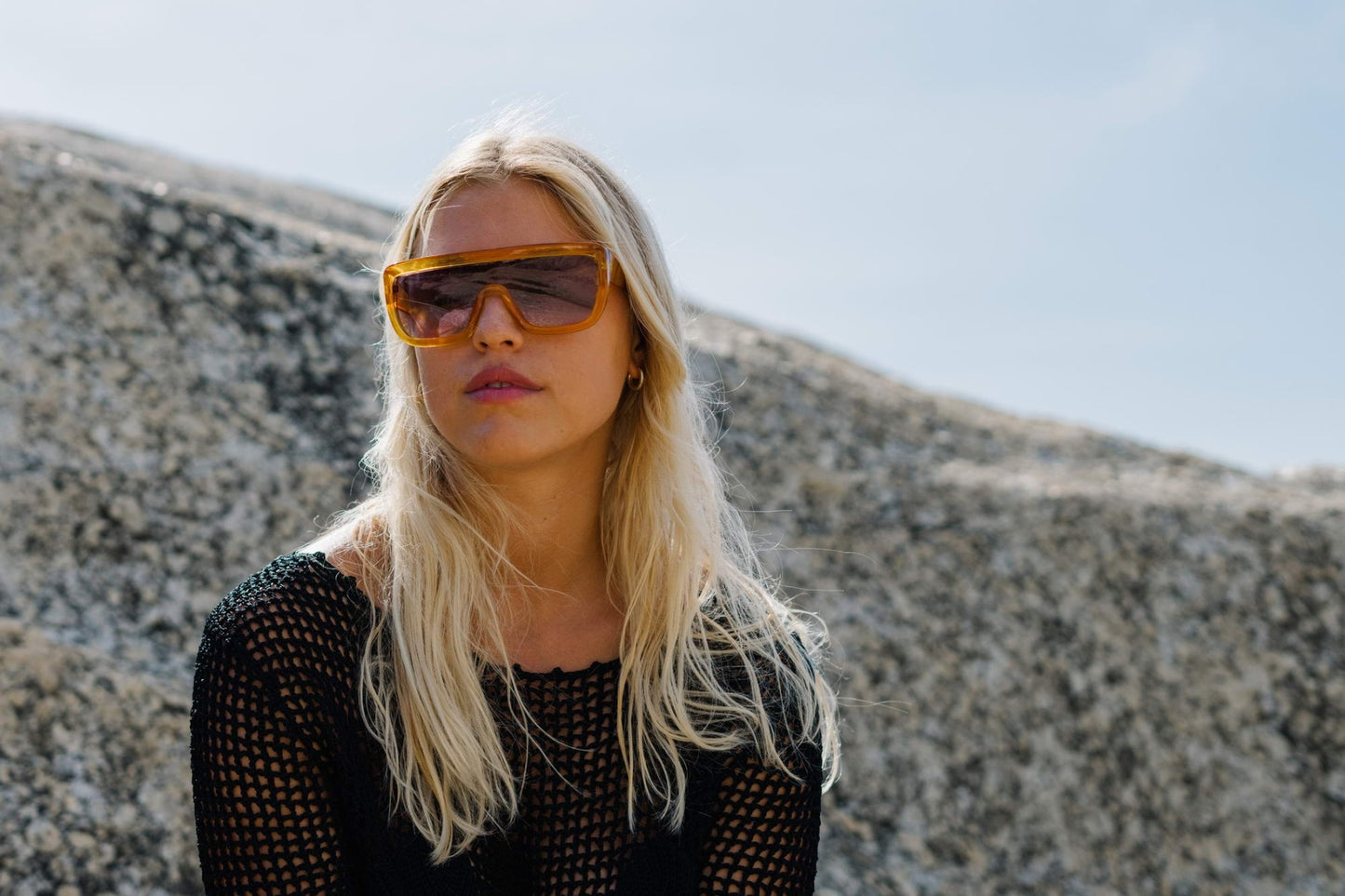 Woman wearing bold oversized sports party sunglasses outdoors — flat-top shield visor in sustainable recycled polyester, the statement frame that owns every outdoor festival, beach club and open-air party | Sunglass Station