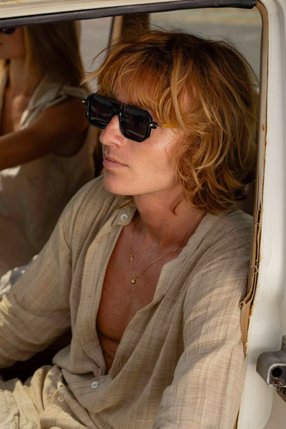 man wearing eco geometric party sunglasses outdoors — effortlessly worn bold navigator frame in recycled polyester, the sustainable eyewear that proves conscious dressing and great style are the same decision | Sunglass Station