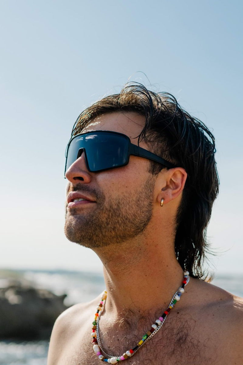 man wearing oversized black sunglass at santorini lake shore