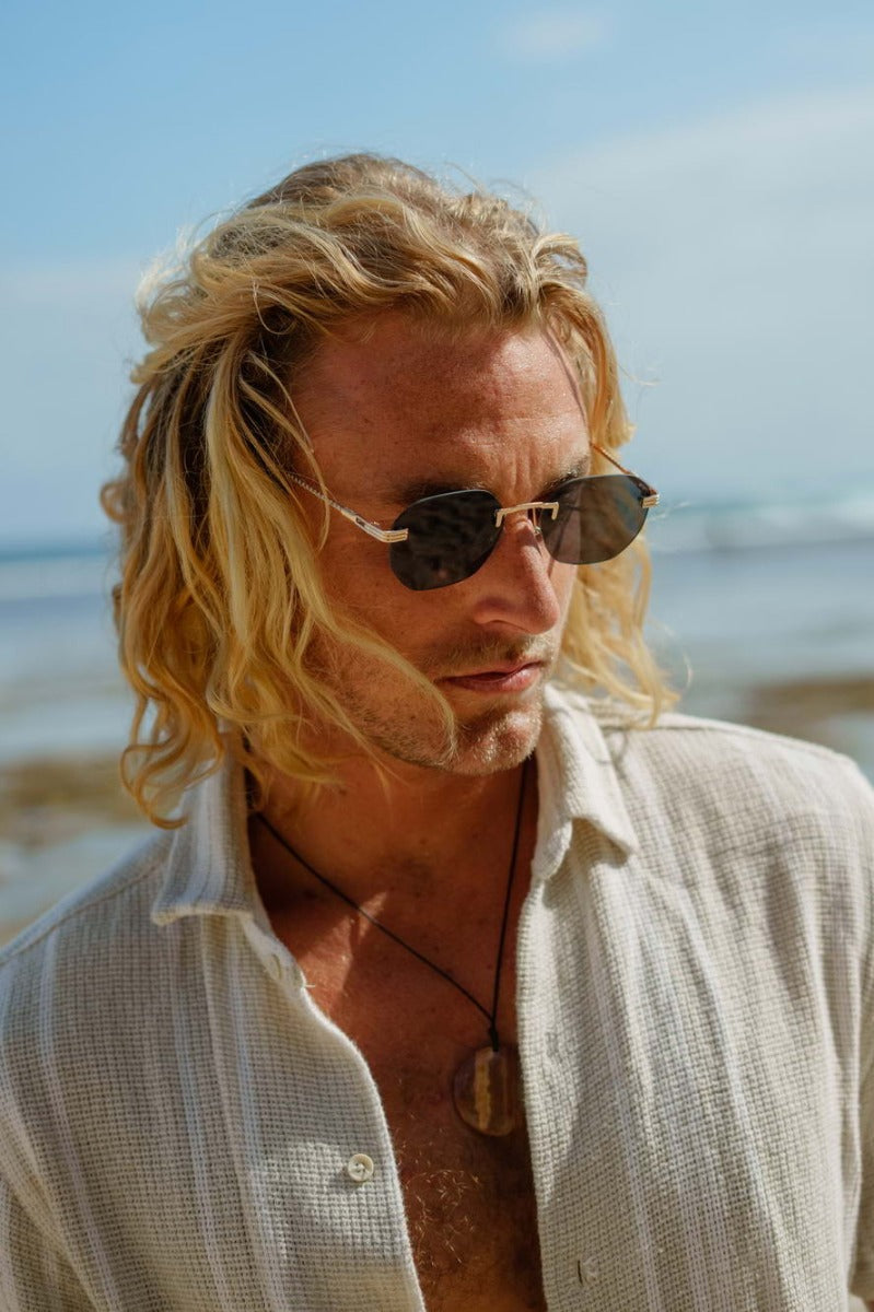 man wearing black geometric sunglasses on a london beach