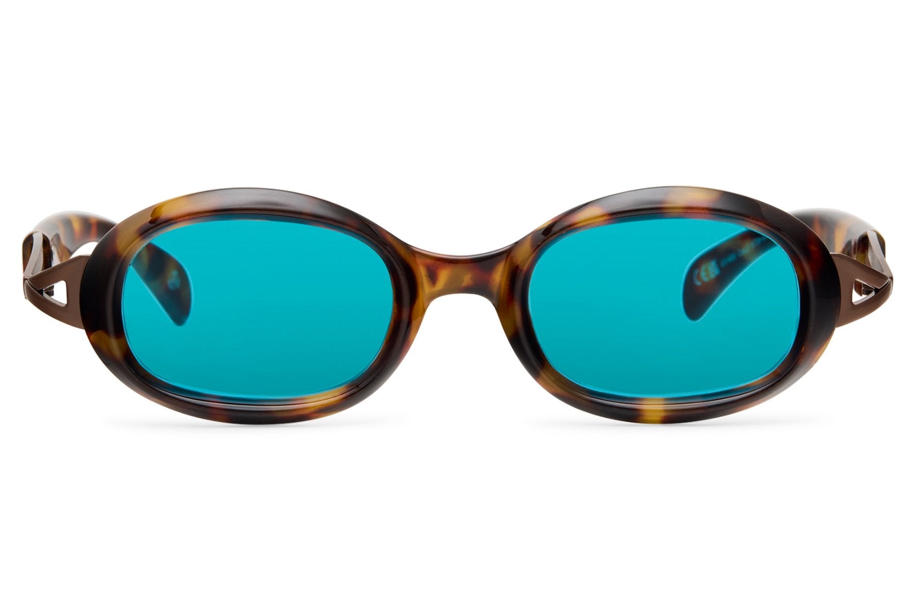 Tortoiseshell bold oval party sunglasses with vivid teal lens — warm frame meets chromatic lens, the colour-blocking combination that defined euro summer dressing from Lisbon to Mykonos in 2026