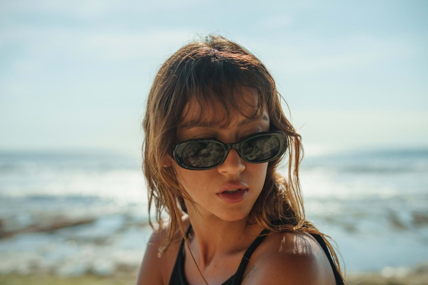 Woman wearing oval trendy sunglasses with black frame and dark smoke UV protection lens – stylish retro round shades for going out and summer holidays, Sunglass Station free UK and Europe shipping