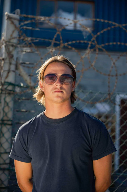 Man wearing aviator sunglasses in city travel setting, stylish metallic frame eyewear perfect for urban outfits and summer travel looks