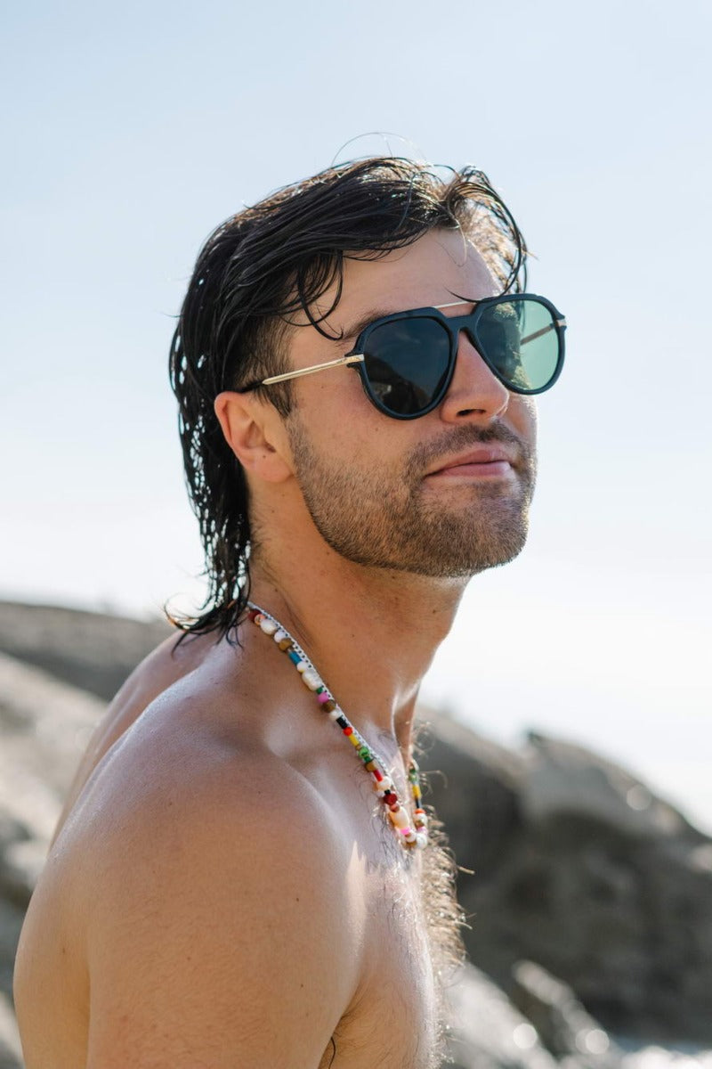 Man wearing bold aviator sunglasses on beach holiday, trendy retro eyewear perfect for influencer style, summer outfits, and vacation looks