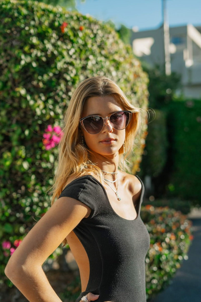 Woman wearing elegant cat eye sunglasses with gradient lenses in outdoor setting, showcasing a chic and confident fashion look
