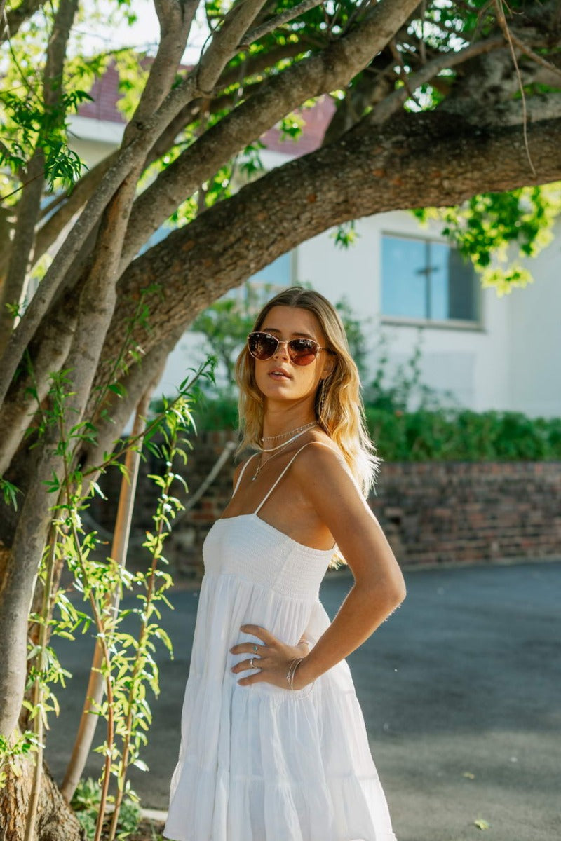Woman wearing brown cat eye sunglasses outdoors in natural light with a relaxed modern style