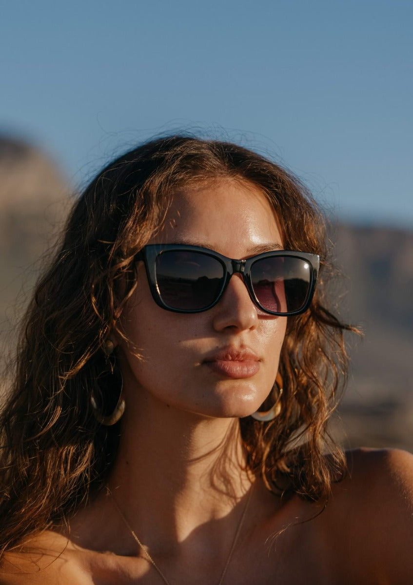 Woman wearing chunky cat eye sunglasses with bold frame in an outdoor setting