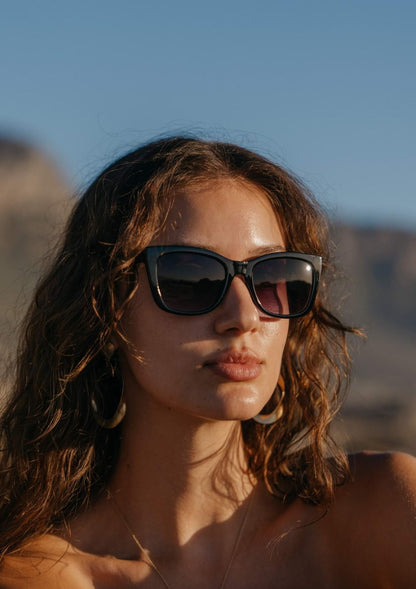 Woman wearing chunky cat eye sunglasses with bold frame in an outdoor setting