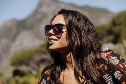 Woman wearing Marilyn-style cat eye sunglasses with purple lenses, showcasing confident glamour and timeless feminine fashion