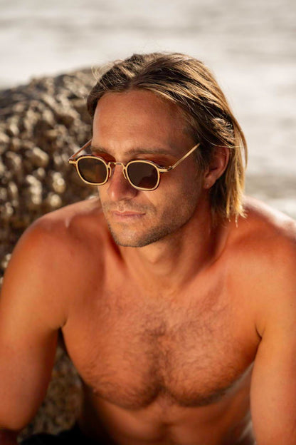 Man wearing retro small square sunglasses with gold frame for beach holidays, travel and relaxed summer outfits