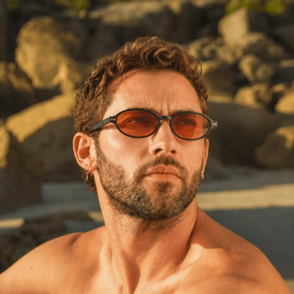 man wearing oval brown sunglasses on a beach